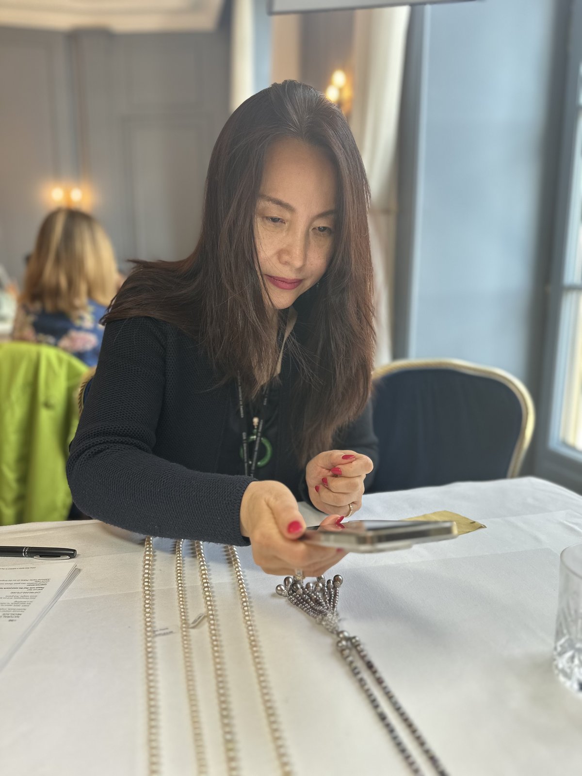 Kehan Li photographing a row of natural pearl strands for client records during the auction preview.